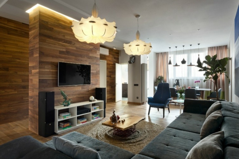 Wohnzimmer mit Wandverkleidung aus Holz und graues Ecksofa